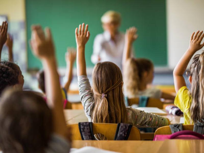 Classroom of kids raising their hands