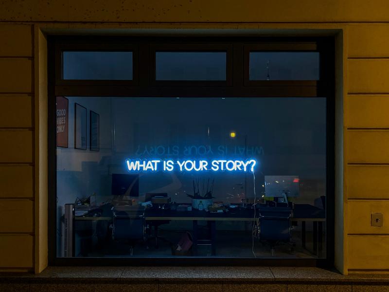 A window with a sign that says "What is your story?"