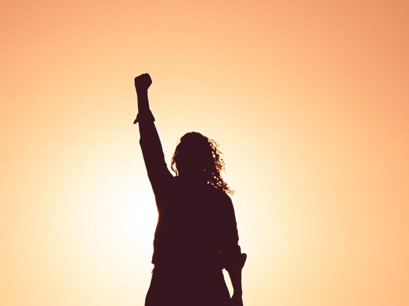 Silhouette of a person with their fist raised in front of a light