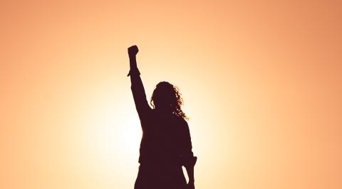 Silhouette of a person with their fist raised in front of a light